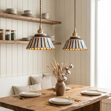 Load image into Gallery viewer, Dining room with wooden table, striped pendant lights, and shelves.