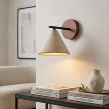 Load image into Gallery viewer, Wallscon wall lamp on a white wall with books and a vase on a table below.
