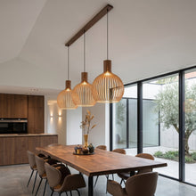 Cargar imagen en el visor de la galería, Modern dining area with wooden table and pendant lights in a well-lit room.
